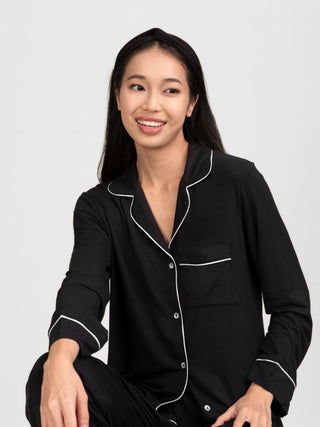 Woman wearing rawbought's black pajamas with white piping