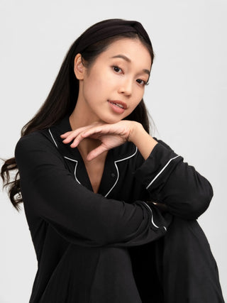 Woman wearing rawbought's black pajama set with white piping and black modal head band