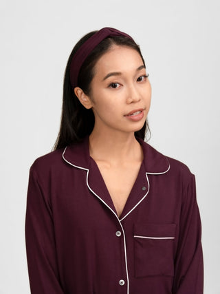 Woman wearing rawbought's burgundy pajama set with white piping with matching burgundy head band