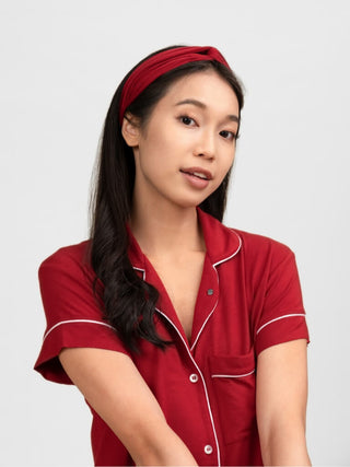 Woman wearing rawbought red pajama set with white trim on a plain background